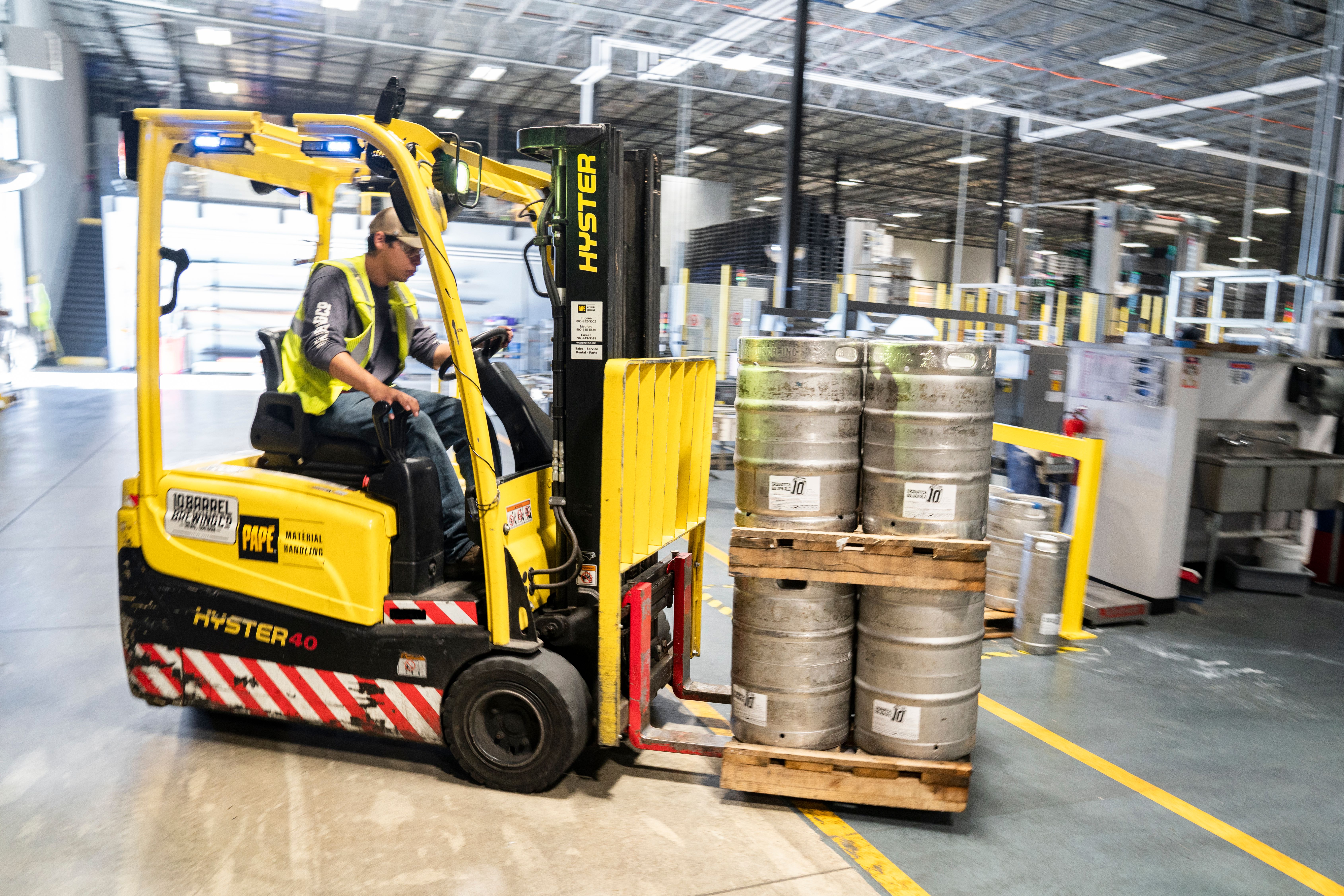 Forklift moving palletized kegs through the warehouse